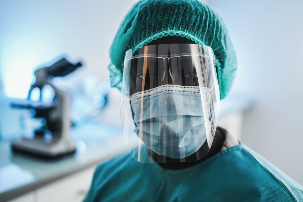 Young african medical doctor working inside hospital lab during coronavirus outbreak - Focus on face